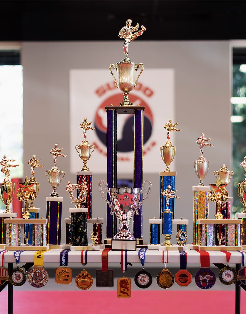 A table filled with taekwondo tournament trophies and medals