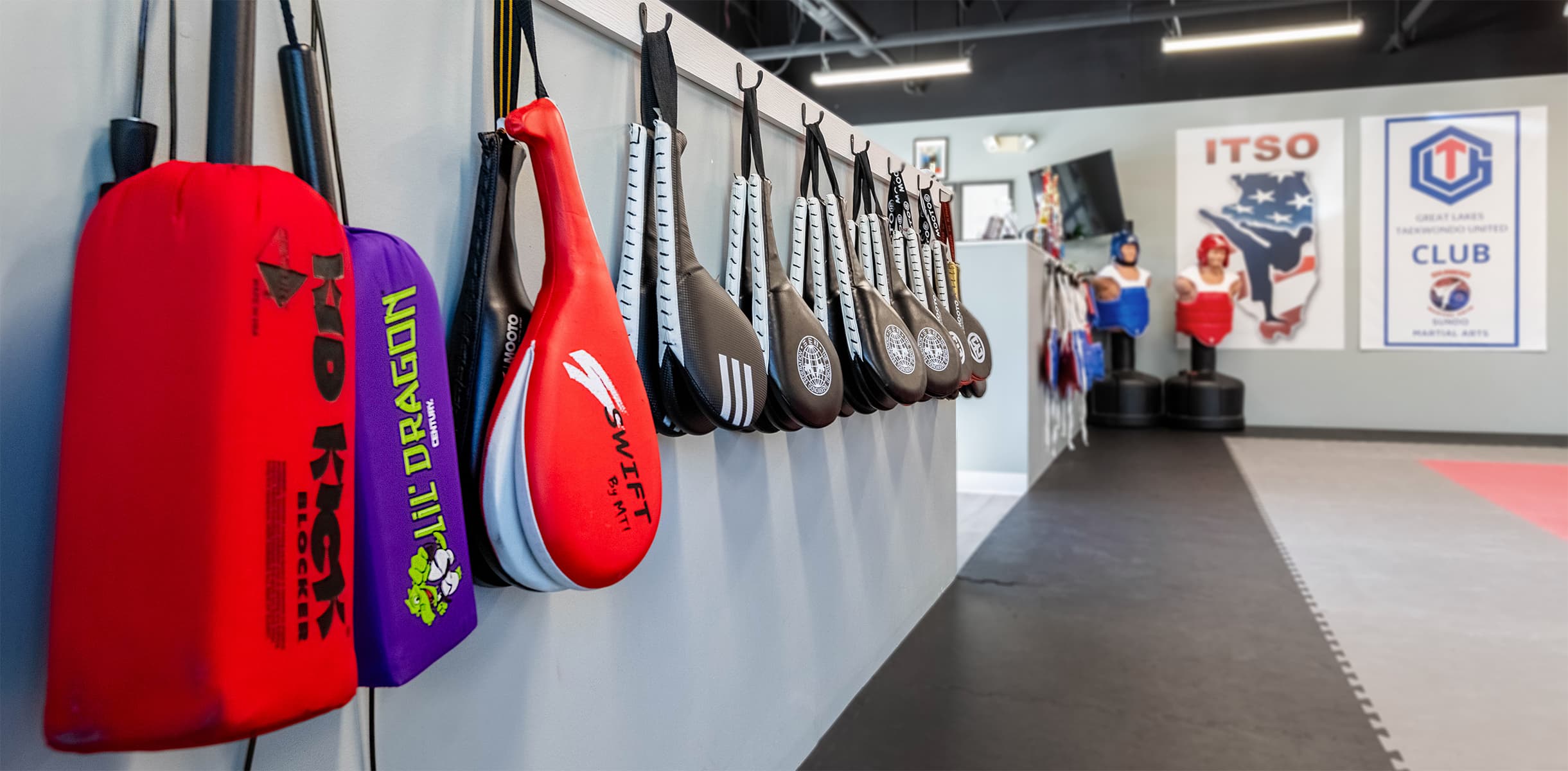 A half wall filled with kicking targets, sparring chest guards, and kicking bags