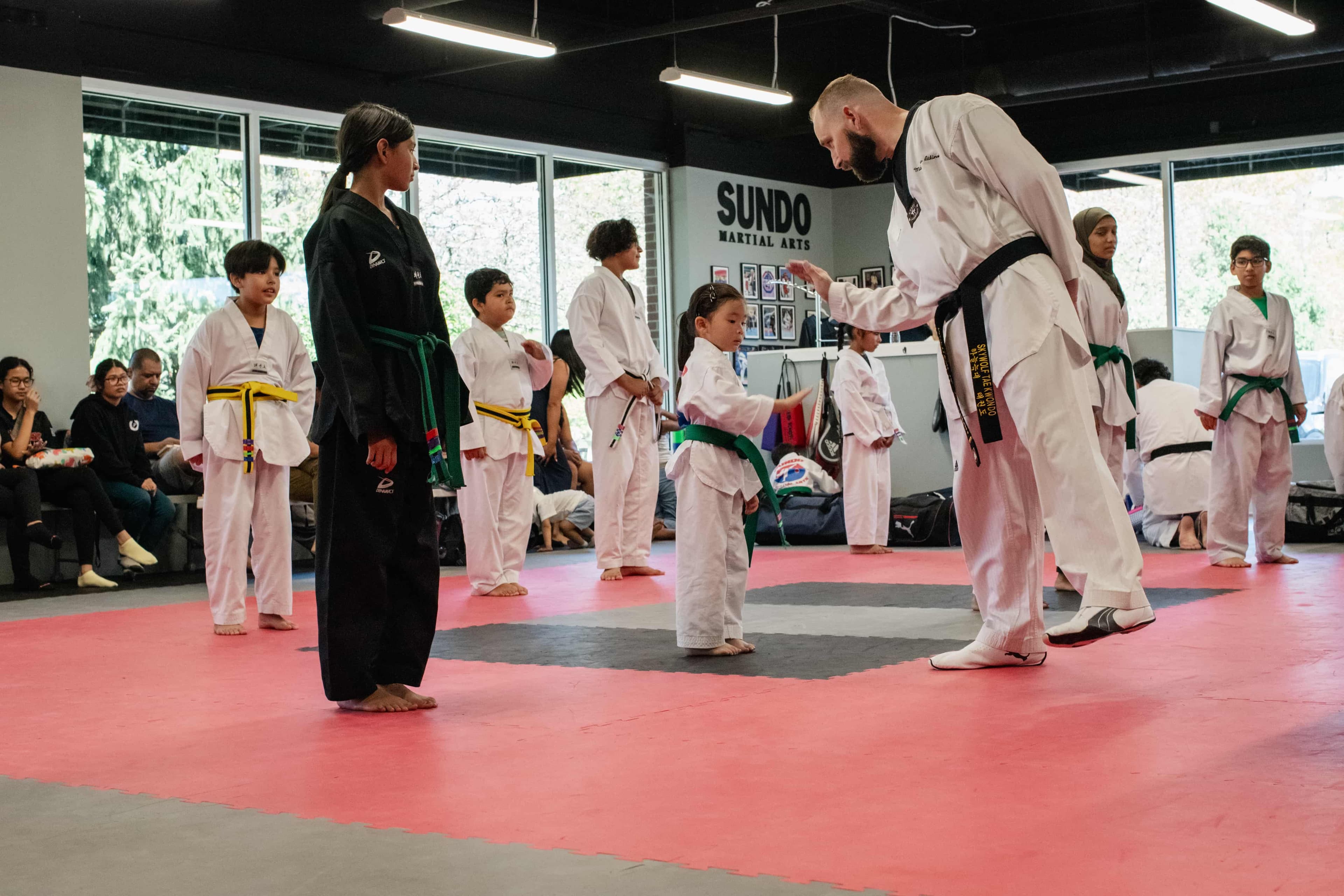 Young Sundo students standing at attention while Instructor Matt high fives them