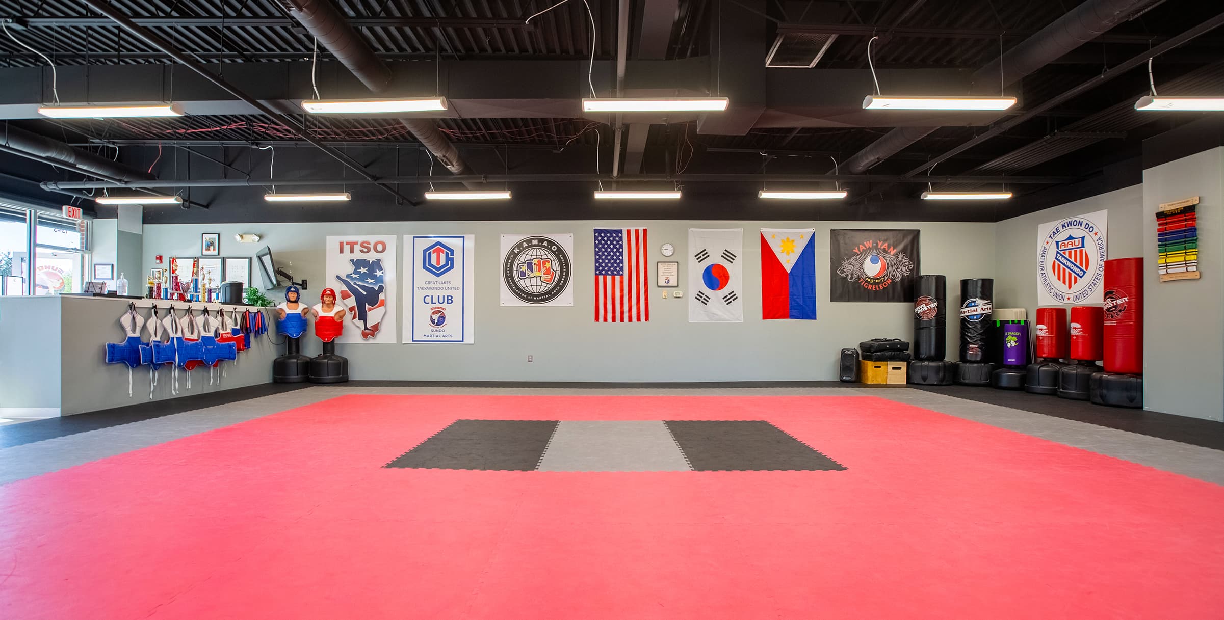 The Sundo Martial Arts school's interior, a wall with sparring gear, a wall with flags, and a wall with kicking bags