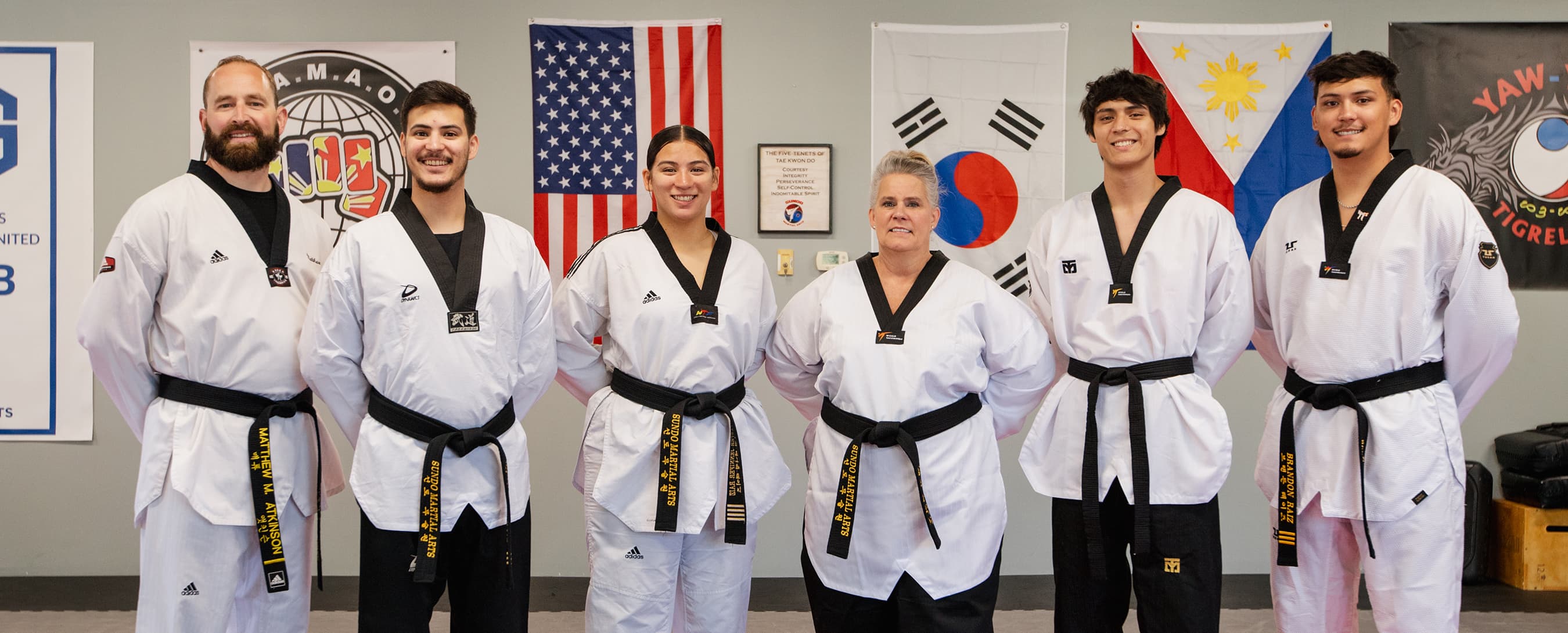 Sundo Martial Arts' instructors standing in front of the american, korean, and filipino flags